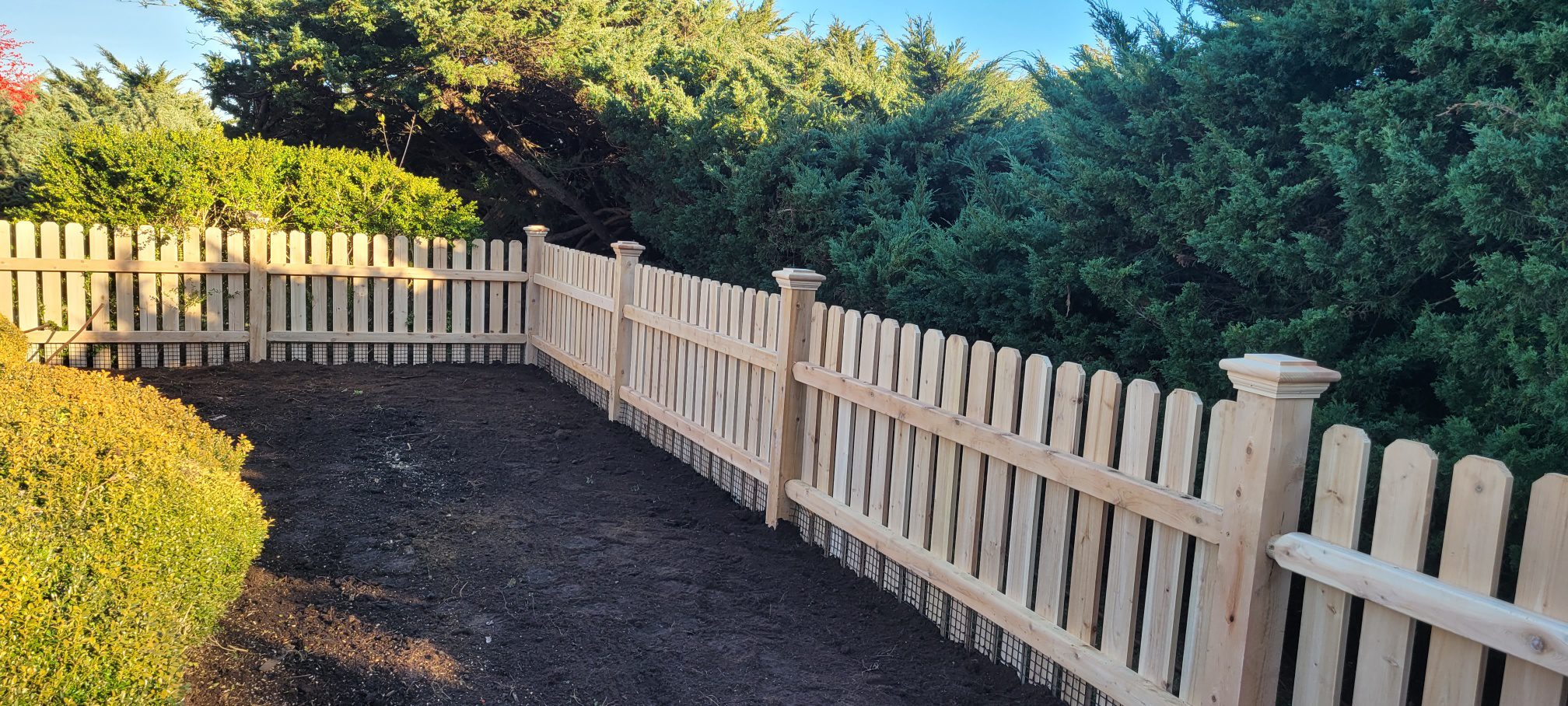 Cedar picket fence with welded wire mesh enclosing a vegetable garden, Arrow Fence Inc